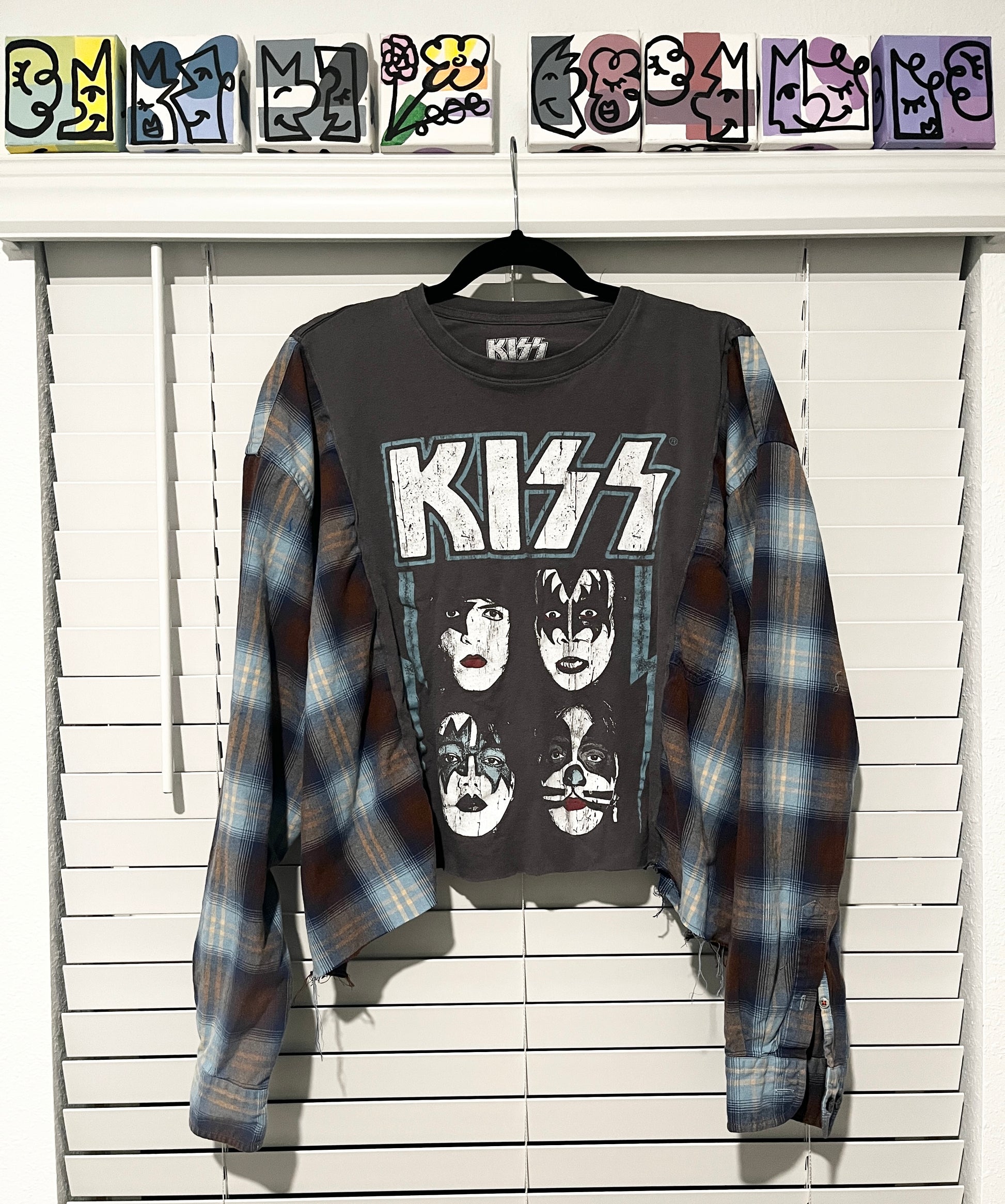 Gray 'KISS' t-shirt with plaid shirt over it on a white wooden background